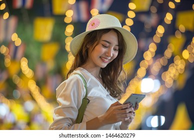 Happy Traveller Young Woman Using Mobile Phone To Taking Selfie At Night Street Market With Light Bokeh Background In Bangkok Thailand.