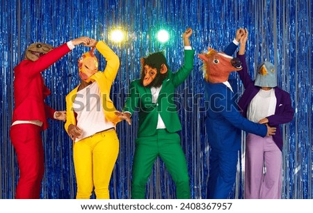 Happy trendy people in colorful party suits and animal masks dancing in nightclub. Group of friends wearing latex monkey, chicken, horse, dinosaur masks having fun on shiny background