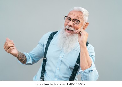 Happy trendy senior man having fun posing in front camera - Fashion beard mature male enjoying retired time - Elderly people lifestyle and hipster culture concept 