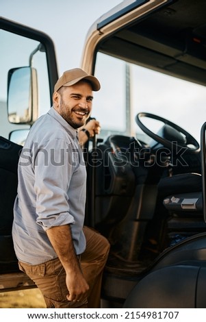 Happy truck driver entering in vehicle cabin and looking at camera.                                                         