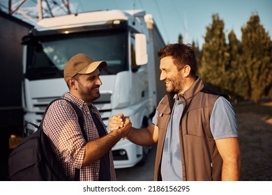 Happy truck driver and his coworker greeting while standing on parking lot.  - Shutterstock ID 2186156295