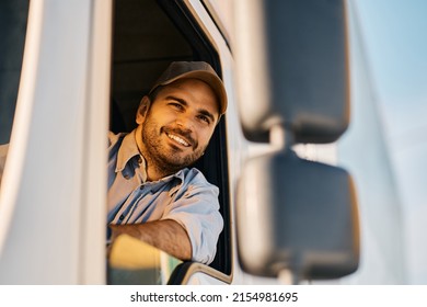 Happy Truck Driver Looking Through Side Window While Driving His Truck. 