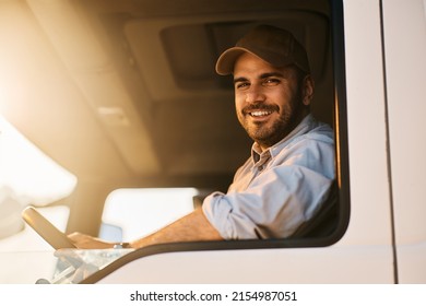 Happy truck driver sitting in vehicle cabin and looking at camera.