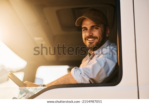 Happy truck driver sitting in vehicle cabin and\
looking at camera.