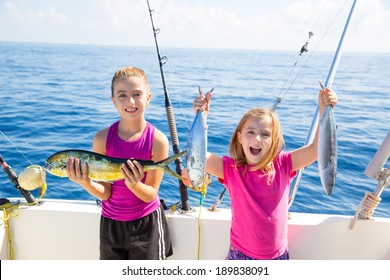 Happy tuna fisherwomen kid girls on boat with fishes trolling catch with dorado Mahi