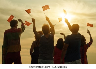 Happy Turkish Family With Flags. Patriotic People Raising Flags To The Evening Sky, Back View.