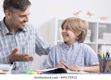 Happy Tutor And Small Boy Sitting Beside Desk During Private Lessons At Home