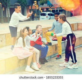 Happy Tween Boys And Girls Having Friendly Discussion During Gathering Outdoors On Autumn Day.