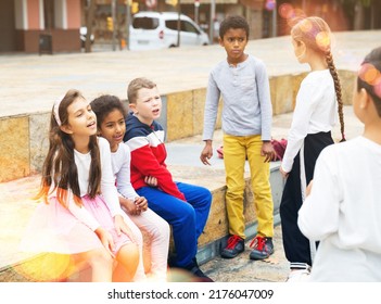 Happy Tween Boys And Girls Having Friendly Discussion During Gathering Outdoors On Autumn Day.