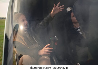 Happy Tween Girl In Aviator Headphones Sitting In Helicopter, Pointing To Sky