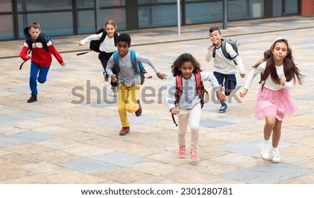 Happy tween schoolchildren of different nationalities with backpacks running together to school lessons outdoors on fall day. Foto stock © 