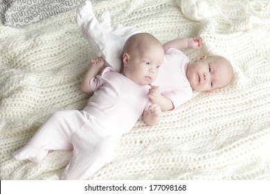 Happy Twin Baby Girls Lying On Back On Their Blanket.