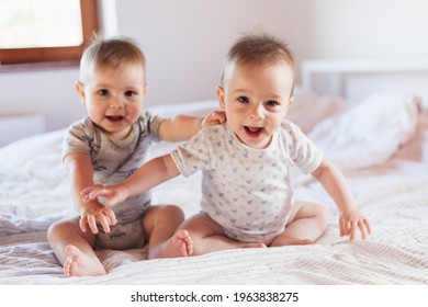 Happy twins, baby boy and baby girl are playing on the bed and laughing