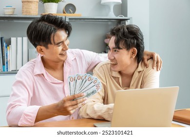 Happy two Asian men gay couple celebrating financial achievement with cash banknote at home - Powered by Shutterstock