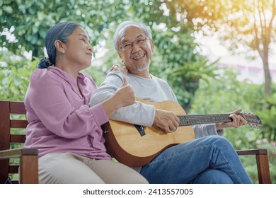 Happy two Asian senior couple elderly man playing the guitar while his wife is singing together at home outdoors, Enjoying lifestyle during retirement life having fun, Activity family health care - Powered by Shutterstock