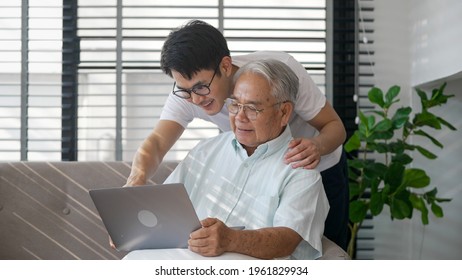 Happy Two Generation Asian Family Son And Old Man Father Enjoying Happily Together Using Tablet, Laptop To Watching Video And Using Applications Social Media.Old Man With Happy Life After Retired.