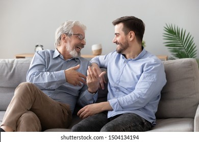 Happy two generations male family old senior mature father and smiling young adult grown son enjoying talking chatting bonding relaxing having friendly positive conversation sit on sofa at home - Shutterstock ID 1504134194