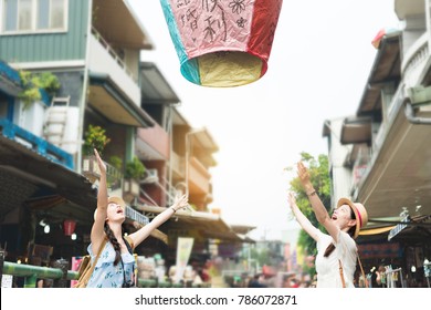 happy two girl release let go the sky lanterns to air. Translation on sky lanterns text "hopes of happiness and good luck in love life in the future".