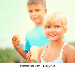 Happy Two Kids Eating Ice Cream And Smiling, Outdoors. Children With Ice-cream Cone Walking Together And Enjoying Icecream In Summer Park