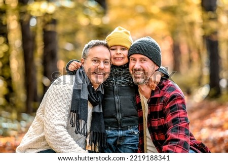 A Happy two man couple with adopted child on autumn season