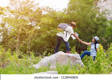 Happy Two Middle Aged In Forest. Couple Active Asian Senior Couple Hiking On The Top Of Rock. Mature Man Helping Woman Climbing Up. Freedom Travel Healthy And Lifestyle Concept.