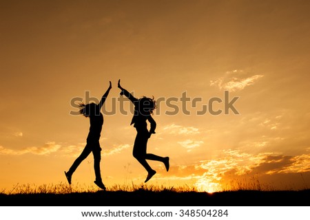 Happy of two women jumping and sunset silhouette with copy space.