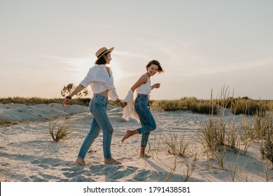 Happy Two Young Women Having Fun On The Sunset Beach, Queer Non-binary Gender Identity, Gay Lesbian Love Romance, Boho Summer Vacation Style Wearing Jeans