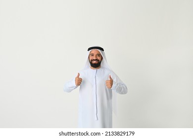 Happy UAE Emirati man thumbs up standing wearing traditional emarati Arab dish dash dress on studio white background - Shutterstock ID 2133829179
