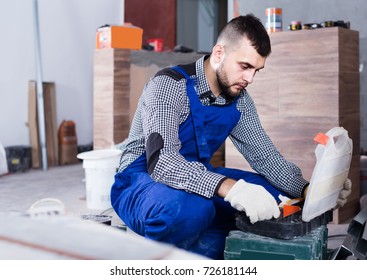 Happy Ukrainian Worker Is Choosing Tools In Suitcase For Work At The Object.