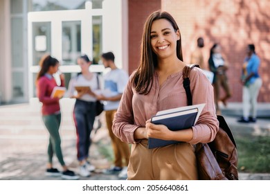 Happy university student going on a class at the university and looking at camera. 