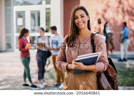 Happy university student going on a class at the university and looking at camera. 