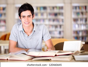 Fröhlicher Student in der Bibliothek, der Bücher liest