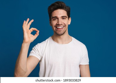 Happy Unshaven Guy Smiling And Showing Ok Sign At Camera Isolated Over Blue Background