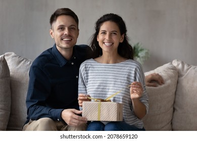 Happy Valentines Day, Anniversary Celebration, Gift Shop Ad Concept. Loving Latin Couple Sit On Sofa With Giftbox Smile Look At Camera, Enjoy Life Event Family Holiday Event And Long Awaited Surprise