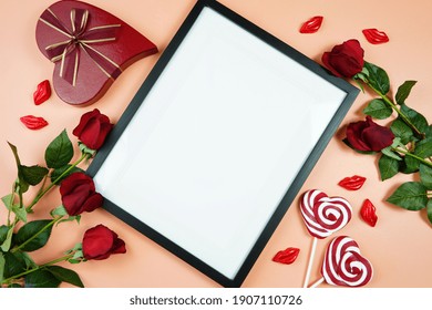 Happy Valentine's Day Black Border Picture Frame, Styled With Valentine Red Roses, Heart Shape Gift And Lipstick Kissess Chocolates On A Modern Coral Background. Mockup. Top View Flat Lay. Copy Space.