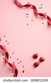 Happy Valentines day card with red ribbon, confetti, heart shaped sweets on pink background. Vertical banner, brochure, poster design.