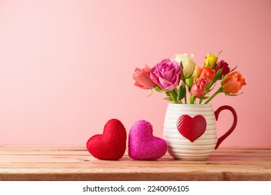 Happy Valentine's day concept with rose flowers and heart shapes on wooden table over pink background - Shutterstock ID 2240096105