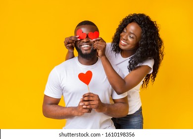 Happy Valentine's Day Darling. Black Pretty Woman Closing Man Eyes With Red Valentine Cards On Yellow Background