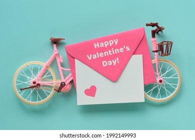 Happy Valentine's Day Toy Model Town Bike Or Tandem On Mint Blue Background. Flat Lay, Top View, Minimal Retro Vintage Concept Design. Text On Card In Pink Envelope With Heart Shape.