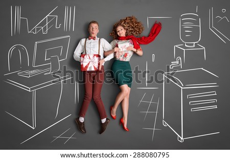 Happy valentines love story concept of an office romance. Young couple at work smiling at each other and sharing presents against chalk drawings background.