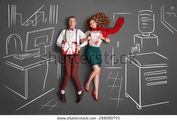 オフィスロマンスの幸せなバレンタインのラブストーリーのコンセプト 白墨の絵の背景に 仕事場の若い夫婦が微笑み合い 贈り物を共有している の写真素材 今すぐ編集