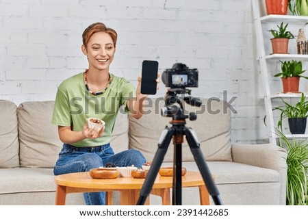 happy vegetarian woman holding smartphone with blank screen during video blog on plant-based diets