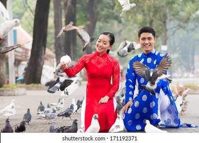 Happy Vietnamese couple among pigeons on the street