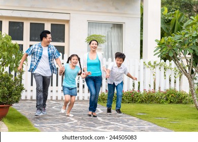 Happy Vietnamese Family Running Together In The Backyard