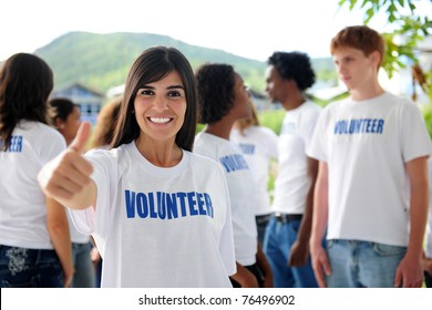 Happy Volunteer Woman Showing Thumbs Up Sign, Group In Background