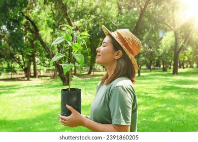 Happy volunteer young asian woman holding small saplings preparing to plant trees in the garden forest to reduce global warming on World Tree Planting Day Volunteer girl doing good service to society. - Powered by Shutterstock