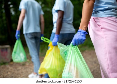 Happy Volunteers Connect After Cleaning Up The Environment In A Public Park, Walk One After The Other And Go To Another Location. Selective Focus