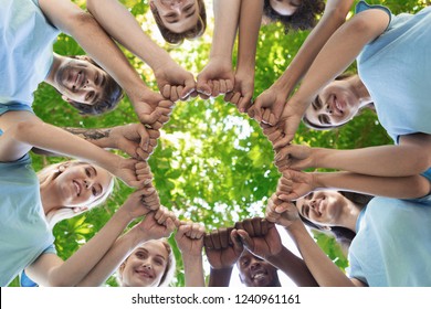 Happy volunteers fist bump together, standing in park and making circle, unity and collaboration concept, copy space