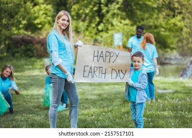 Happy Volunteers Holding Placard With 'happy Earth Day' Message. Group Of People, Cleaning Together In Public Park, Saving The Environment Together. Happy Earth Day!