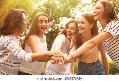 Happy volunteers putting hands together outdoors on sunny day - Powered by Shutterstock